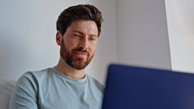 Yatakta dizüstü bilgisayar başında gülümseyen ve ev içi tembelliklerinin keyfini çıkaran serbest çalışan biri. Mutlu sakallı adam yastık kılıfı yatak odasında e-posta yolluyor. Uyanık esmer daktilo bilgisayarı tek başına aydınlık dairede.