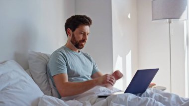 Sabah adamı laptopunu yatakta uygulamayı izlerken sakin bir hafta sonu ev kapanışı yapmayı düşünüyor. Rahat iş adamı, bilgisayardaki e-postaları cevaplıyor ve beyaz yatak örtüsünde yatıyor. Serbest çalışan mutlu yatak odası