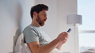 Sabahçı adam rahat bir yatakta cep telefonuna bakıyor ve kendini hayal kırıklığına uğramış hissediyor. Sinirli adam akıllı telefonu rahat bir yatağa koyuyor. Üzgün esmer, evde yalnız başına cep telefonunda SMS okuyor.