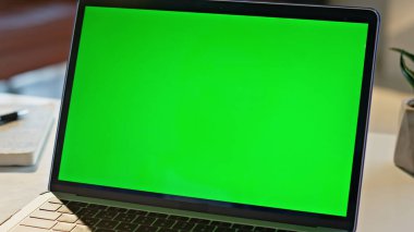 Modern yeşil ekran dizüstü bilgisayarı yakın çekim masasına yerleştirildi. İçerideki çalışma masasında açık olan bilgisayar görüntüsü görüntüsü. Boş kroma anahtar not defteri monitörü şirket işi için hazır. Dijital teknoloji
