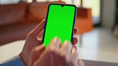 Akıllı telefonları dinleyerek yeşil ekran taraması çevrimiçi daire kapanışı uygulaması. Modern evde elinde krom anahtarlı cep telefonu olan tanınmayan bir iş adamı. Model etkileşimi için boş ekran