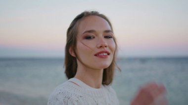 Huzurlu bayan okyanus sabahından zevk alıyor. Güneş doğarken yakın planda poz veriyor. Kendine güvenen bir kadın okyanus güzelliğini rüzgarlı bir alacakaranlıkta seyrediyor. Esmer, örgü elbiseli, sahilin manzarasında dinginlik hisseden..