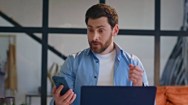 Gülümseyen bir acemi, daire kapatıldığında cep telefonu ekranına bakıyor. Aşırı mutlu serbest çalışan adam, akıllı telefon başarısını kontrol ediyor. Mutlu yönetici iç mekanda seviniyor.