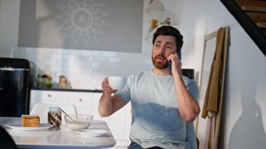 Rahatlamış bir adam kahvesini yudumlarken mutfaktaki akıllı telefonu arıyor. Apartman mutfağında oturan pozitif adam cep telefonuyla sabah içkisini içiyor. Sakin erkek kahvaltıda telefonda haberleri tartışıyor. 