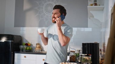 Rahatlamış serbest çalışan akıllı telefonlardan konuşuyor sabahları yakın plan kahve içiyor. Orta yaşlı yakışıklı bir adam cep telefonunu arıyor ve hafif mutfakta içkinin tadını çıkarıyor. Neşeli adam cep telefonunu tek başına kullanıyor.