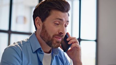 Gülümseyen adam ev portresi için arıyor. Modern apartman dairesine yakın oturan akıllı telefondan iş görüşmesi yapmaktan mutlu. İçerideki konferansta el kol hareketi yapan olumlu adam.