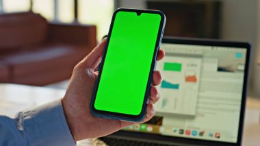 Cep telefonu kullanıcısı ev ofis kapanışında internette sörf yapıyor. Açık iş yerinde yeşil ekran akıllı telefonu dinleyen tanınmamış bir serbest çalışan. Ellerinde krom anahtarı olan cep telefonu
