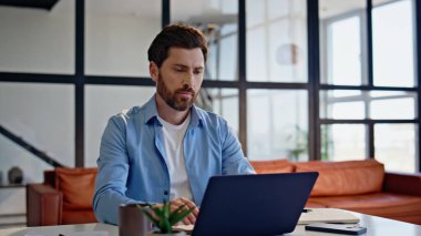 Merkezi ofis iç çekimlerinde modern dizüstü bilgisayarı yazan yaratıcı ilham kaynağı. Yakışıklı sakallı adam yönetici masadaki bilgisayar ekranına bakıyor. Düşünceli geliştirici kod düşünme projesi yazıyor