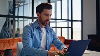 Ev ofisinin iç kısımlarında modern dizüstü bilgisayarda daktilo kullanan odaklanmış bir yönetici. Masada bilgisayar ekranına bakan yakışıklı genç adam. Çok mutlu bir serbest çalışan cep telefonu uyarısını kontrol ediyor.