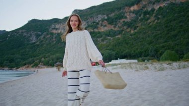 Akşamları deniz kıyısında gezinen bir kız kameraya gülümsüyor. Kumsalda kumsalda yürüyen mutlu bir kadın. Kıyı şeridine giden rahat bir tatilci yaz sabahı yeşil tepeleri tek başına sarmıştı..