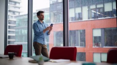 Ofis çalışanı panoramik pencerenin yanında duran akıllı telefondan maaş bildirimi alıyor. Gülümseyen işadamı cep telefonu mesajını okuyor. İş molasında sosyal medya içeriğine göz atan yakışıklı adam yöneticisi.