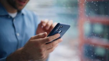 Mutlu yönetici görünümlü akıllı telefon ofis penceresinin yanında duruyor. Gülümseyen işadamı cep telefonundan iyi haberler alıyor. Binada cep telefonu uygulamasına bakan neşeli bir adam..