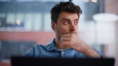 Odaklanmış programcı kod görünümlü dizüstü bilgisayarın yakın plan çekimini düşünüyor. Ofis panoramik penceresinin yanında oturmakla meşgul ciddi geliştirici. Yakışıklı iş adamı iş çözümlerini içeride düşünüyor.