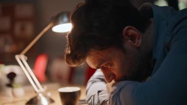 Uykulu çalışan gece geç saatlerde iş yerinde oturuyor. Çok çalışan iş adamı gece ofisinde lamba ışığında el ele tutuşuyor. Yorgun adam serbest çalışan iş meseleleri hakkında endişeli son teslim tarihi.