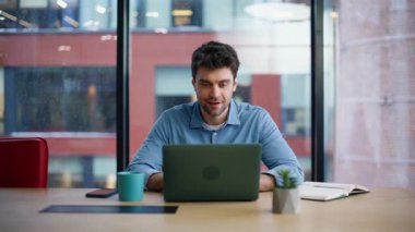 Gülümseyen yaratıcı ofis panoramik penceresinin yanında oturan dizüstü bilgisayarı görüyor. İş yerindeki bilgisayarda çalışan ilham verici bir menajer. Çalışma alanında bilgisayar oluşturma projesinde başarılı iş adamı.