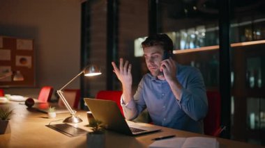 Fazla çalışan çalışan cep telefonuyla konuşuyor. Gece geç saatlerde çalışma alanında dizüstü bilgisayar ekranı görünüyor. Stresli yönetici endişeli telefon görüşmesini bitirdi. Aşırı yüklü işadamı fazla mesai yapmaktan bıktı..