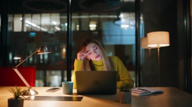 Aşırı yüklenmiş yönetici çözümleri gece geç saatlerde ofiste çalışıyor. Mutsuz iş kadını, karanlık iş yerinde dizüstü bilgisayara bakıyor. Geceleri kod yazan yorgun kadın programcı. Fazla mesai konsepti.