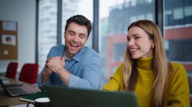Dost canlısı meslektaşlar ofis iş yerinde dizüstü bilgisayarın keyfini çıkarıyorlar. Gülümseyen iş arkadaşları projede işbirliği yapıyor. Mutlu ekip kurumsal işyerinde işbirliğini tatmin etti.