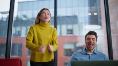 Ofis ortakları şirket işyerindeki dizüstü bilgisayar görüntülerini kutluyorlar. Mutlu kadın erkek birlikte iş zaferine seviniyor. Gülümseyen heyecanlı iş arkadaşları başarılı takım çalışmasının keyfini çıkarıyorlar..