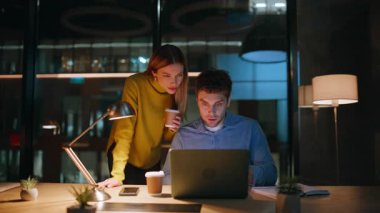 Aşırı mutlu iş arkadaşları, karanlık işyerinde beş sevinçli iş başarısı sağlıyor. Ofis bilgisayarında kahve fincanı arayan iki işçi heyecanlı. Duygusal kazananlar gece iş yerinde harika haberlere tepki veriyorlar.