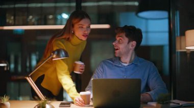 Eşi kocasına kahve getiriyor. Gece geç saatlerde bilgisayarda çalışıyor. Yakın plan. İki meslektaş elinde bardak içeceği ile Karanlık Gece Ofisi 'nde yaratıcı projeyi tartışıyorlar. Başlangıçta işbirliği yapan gülümseyen iş arkadaşları.