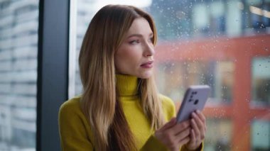 Sakin bir serbest çalışan cep telefonuna benziyor. Yakın çekimde uyarı alıyor. Rahatlamış güzel bir kadın cep telefonuna göz atıyor yağmurlu pencereden şehir manzarasının tadını çıkarıyor. Akıllı telefon tutan portre işkadını..