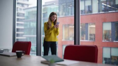 Cep telefonuna bakan hayal kırıklığına uğramış iş kadını kötü haberden endişeleniyor. Hüsrana uğramış iş kadını cep telefonu mesajını okuyor ofis penceresinden stres hissediyor. Ekonomik sorunlar yüzünden depresyonda olan kadın..