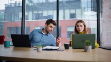 İki çalışan iş yerinde yakın çekimde iletişim kuruyor. Şirket yöneticisi, açık alanda birlikte çalışan bir kadınla fikir paylaşıyor. Çalışma arkadaşları iş projelerini masada dizüstü bilgisayarlarla tartışıyor..
