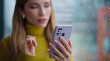 Cep telefonuyla alışveriş yapan bir kadın apartmanın penceresinin önünde dikiliyor. Rahatlamış bir bayan internet mobil uygulamasında sipariş veriyor. Güzel iş kadını kapalı alanda akıllı telefondan iş e-postası okuyor.