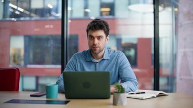 Şirket çalışanı dizüstü bilgisayara bakıyor ve projeyi yakından düşünüyor. Bilgisayarda çalışan ciddi bir iş adamı panoramik pencereli bir ofiste oturuyor. Odaklanmış yönetici iş çözümleri üzerinde kafa yoruyor.