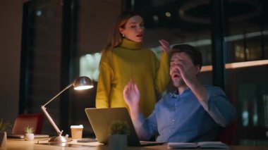 Ofis ekibi, gece iş yerinde birlikte çalışmanın başarısızlıkla sonuçlanacağından endişeleniyordu. Stresli meslektaşlar karanlık çalışma alanlarında duygusal tepkiler veriyorlar. Gergin adam dizüstü bilgisayarı kapatıyor..