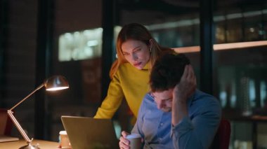 Karanlık ofis alanlarında dizüstü bilgisayara bakan endişeli iş arkadaşları. Kadın akıl hocası, erkek yöneticiye gece işyerinde iş meselelerini çözmesinde yardım ediyor. Fazla mesai yapan iki meslektaş kahve fincanı tutuyor.