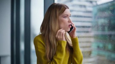 Panoramik pencerenin önünde akıllı telefondan bağıran öfkeli kadın. Deli iş kadını cep telefonuyla bağırıyor iş başarısızlığı yüzünden gergin. Öfkeli kadın yönetici telefon görüşmesine duygusal tepki veriyor..