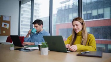 Ofiste dizüstü bilgisayarda çalışan dost canlısı iş arkadaşları yakın plan çekimde. Erkek kadın yöneticiler şirket iş yerinde online araştırma yapıyorlar. İki meslektaş kahve masasında oturan bilgisayarlara odaklanmış..