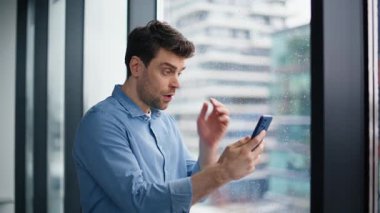 Şaşırmış girişimci cep telefonundan mesaj alıyor koridor penceresinin önünde bekliyor. Endişeli iş adamı akıllı telefon e-postalarını okurken stresli hissediyor. Hüsrana uğramış erkek CEO duygusal olarak kötü haberlere tepki veriyor..