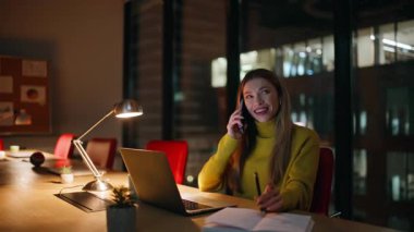 Gece müdürü dizüstü bilgisayarla cep telefonuyla iş yerinden konuşuyor. Gülümseyen iş kadını cep telefonunu arayıp karanlık ofiste projeyi tartışıyor. Akıllı telefondan konuşan kadın fazla mesai yapıyor..