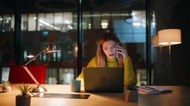 Ofiste cep telefonuyla konuşan bir çalışan dizüstü bilgisayar arıyor. Yorgun iş kadını cep telefonunu arıyor lamba ışığı altında bilgisayarla çalışıyor. Yorgun kadın yönetici gece geç saatlerde akıllı telefondan konuşuyor..