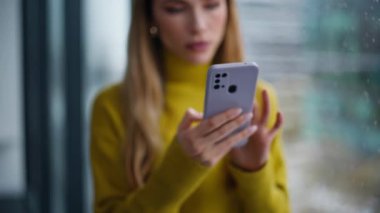 Şok olmuş ezik görünümlü cep telefonu ekranı dairede tatminsiz kötü haberler veriyor. Sinirli kadın ofis penceresinde akıllı telefon mesajı okuyor. Karışık iş kadını mali kaybından endişeleniyor.