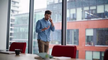 Endişeli serbest çalışan cep telefonu konuşuyor modern çalışma alanı ve şehir manzarası. Sorunlu iş adamı iş hatasını telefonla tartışıyor. Akıllı telefondan ciddi yöneticilerin endişeli haberleri duyması.