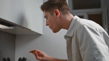 Adam sobada ev yapımı yemek tadıyor. Evde yemek pişirmeye odaklanmış bir adam. Akşamları ahşap kaşıkla yemek tatmaya çalışan düşünceli bir şef. Gündelik erkek modern mutfakta lezzetli yemekler hazırlıyor..