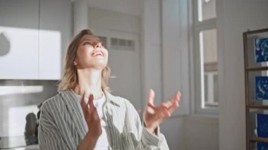 Parlak mutfakta elinde anahtar tutan mutlu kadın. Yakından gülümseyen kız yeni ev aldığı için seviniyor. Güneş ışığındaki neşeli güzel bayan ipotek anlaşmasının keyfini çıkarıyor. Genç yetişkin modern dairede heyecanlı hissediyor.