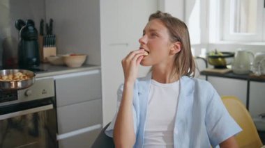 Ev mutfağında lezzetli yemekler yiyen bir kadın. Pijamalı gülümseyen kız tavadan abur cubur yiyor erkek arkadaşıyla konuşuyor. Tanımlanamayan ortak sabah aile için kahvaltı hazırlıyor. Evli çiftler rutini.
