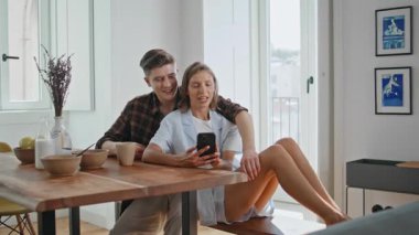 Mutfakta telefon eden mutlu bir çift. Neşeli erkek kadın kahvaltıdan sonra internette geziniyor. Yemek masasında oturan akıllı telefonları kullanan genç eşler. Sevgi dolu sevgililer içeride konuşur.