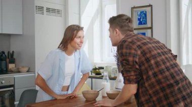 Mutlu çift güneşli mutfakta şakacı şakacı konuşuyor. Evli insanlar hafta sonu sabah gülüp flört ediyorlar. Neşeli kız arkadaş bakışlı erkek gözleri evde eğleniyor. Romantik eşler birlikte vakit geçiriyorlar..