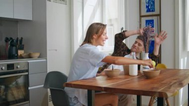 Neşeli çift kahvaltıda eğleniyor. Mutlu erkek kadın yemekle oynuyor modern mutfakta neşeli anları paylaşıyor. Gülen eş, neşeli kocaya çilek fırlatıyor. Hafta sonu aile bağları