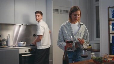 Mutlu çift ev mutfağında şarap tadıyor. Gülümseyen sevgililer romantik akşam yemeği pişirip birlikte eğleniyorlar. Gülümseyen eş bardağa kırmızı içecek dolduruyor. Aile kutlaması yıldönümü..