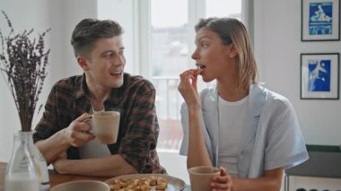 Yeni evliler kahvaltılarının tadını çıkarıyorlar. Kahve içen neşeli çift sıcak mutfakta tatlı yiyor. Güzel kız yemeğini kaygısız erkek arkadaşıyla paylaşıyor. Romantik ilişki yaşam tarzı.