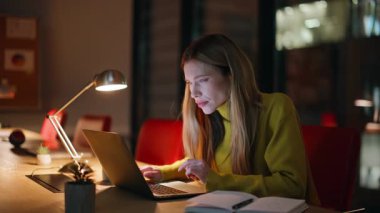 Karanlık ofiste çalışan iş kadını dizüstü bilgisayarı yakından izliyor. Gece vardiyasında bilgisayar kapağı esnemekten yorgun düşmüş. Çok çalışan kadın girişimci uykulu hissediyor. İnternetteki işini bitir..