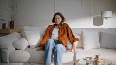 Yorgun kadın parlak oturma odasında oturuyor. Sakin atmosferde, beyaz, rahat ev kanepesine düşen sıradan bir esmer. Güzel genç bayan yorucu bir iş gününden sonra evin içinde dinleniyor..