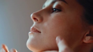 Günlük cilt bakımı rutininde masaj yapan kadın elleri. Evdeki kırışıklıkların önlenmesi için kadın yüz masajı. Sakin esmer kadın sabah tuvaletinde kaldırma işleminden zevk alıyor..